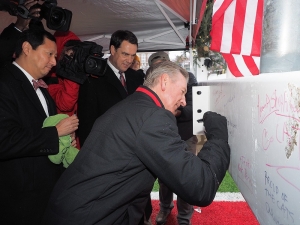 UC officials sign a piece of steal before it is raised up at Nippert Stadium.