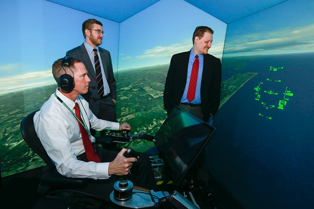 Nick Ernest, David Carroll and Gene Lee in a flight simulator.