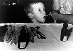 A child, on a Sabin Sunday, receiving a spoonful of pink syrup treated with a life-saving polio vaccine, developed by UC researcher Albert Sabin.