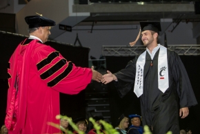 UC President Neville Pinto shakes a graduate's hand. 