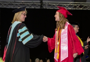 A graduate shakes her dean's hand.