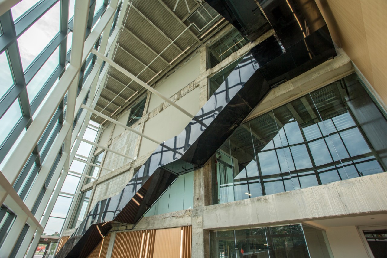 A black staircase with three landings spans the width of the open lobby of the 1819 Innovation Hub. Opposite the staircase is the building's glass facade. 