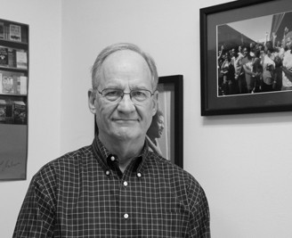 Black and white image of Craig Flournoy standing in front of a photo of civil rights protesters