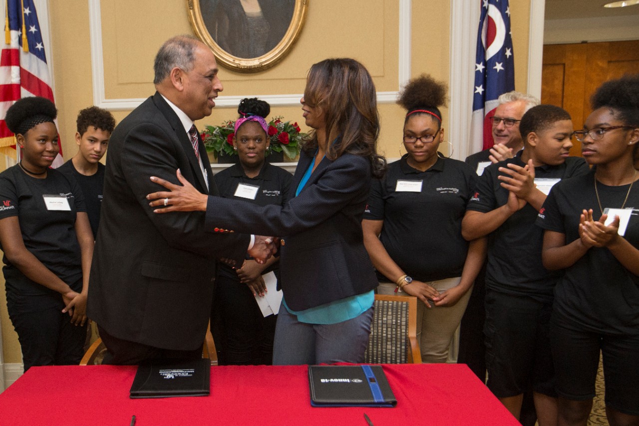 UC President Neville Pinto, left, and CPS Superintendent Laura Mitchell shake hands after signing the agreement formalizing the creation of the Early College Information Technology program.