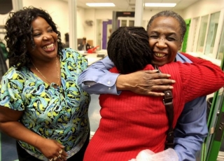 David Ayers, wearing a giant smile, hugs two family members.