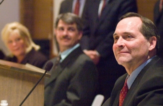 A closeup of Jim Petro's face with Clarence and Melissa Elkins in the background.