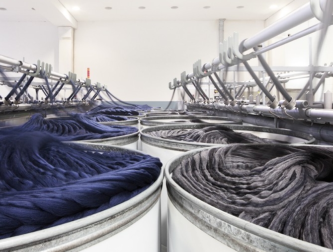 Dark blue and grey wool material is made in large containers at an Italian textile mill.