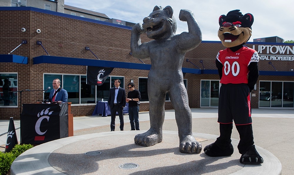 The Bearcat mascot stands next to the new Bearcat statue on Short Vine Street in Corryville, while UC President Ono and UC alumnus sculptor Tom Tsuchiya look on.