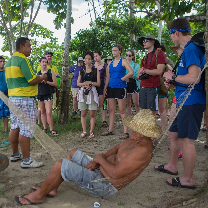 Man hangs in a hammock as students surround him.