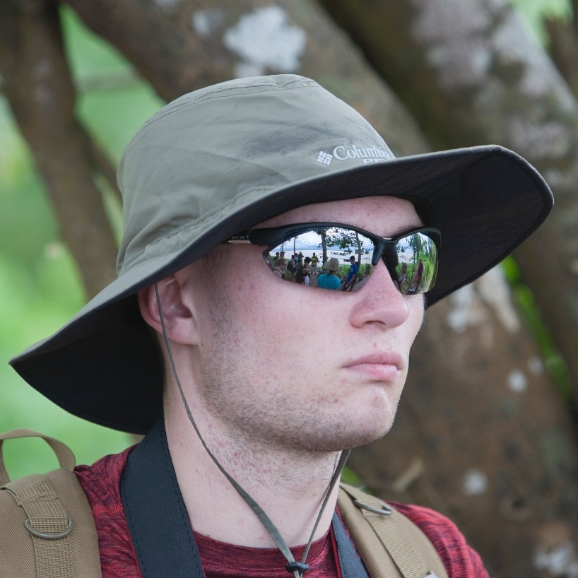 Student looks into the distance, reflections on his sunglasses.