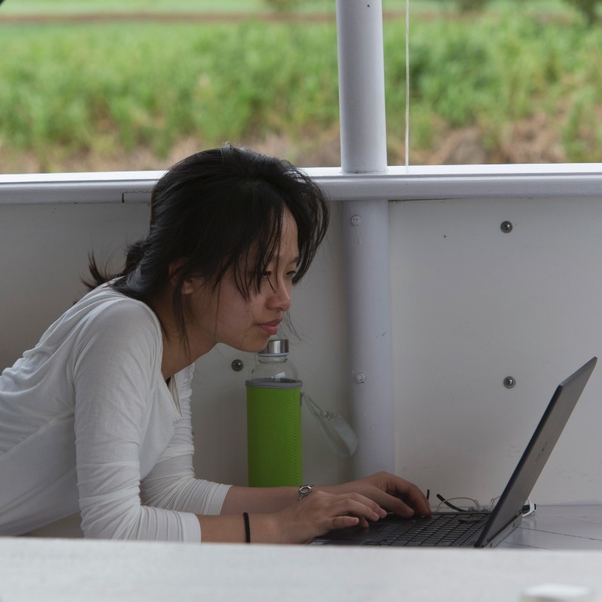 Student works on a laptop on the deck of a boat.