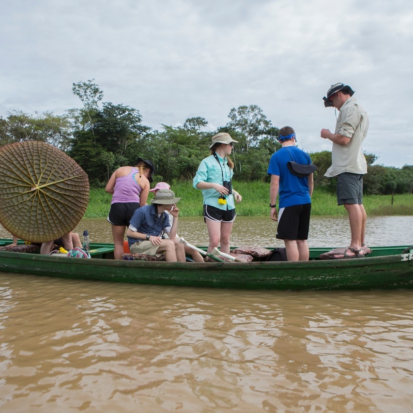 Students float down the Amazon on a motor boat.