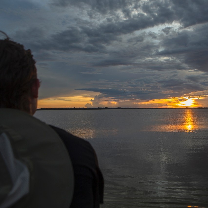 Student profile looking off into a sunset over the Amazon river.