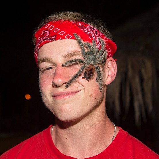  A student poses while a tarantula crawls across his face.