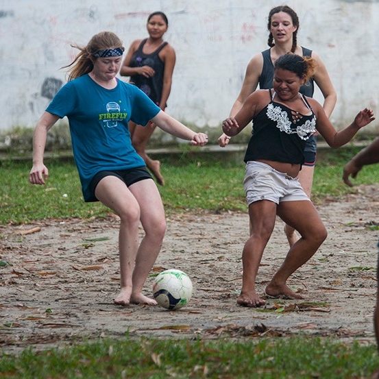 Student kicks a soccer ball during a game with the locals. 