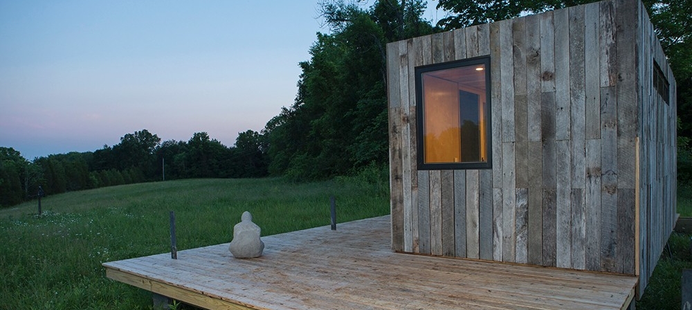 A side view of the tiny house and deck on Kamama Prairie as the sun sets.