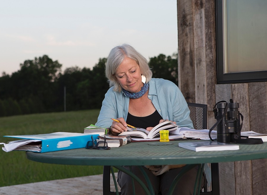 Cassel spends her time off site as a professor at Sinclair Community College. Photo/Andrew Higley/Creative Services Land steward Adrienne Cassel sits at a table on a deck in the Kamama Prairie doing school work.