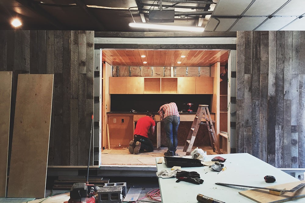 Students work on the tiny house's kitchen as the under-construction home sits in a workshop. Students work on the tiny house's kitchen as the under-construction home sits in a workshop.