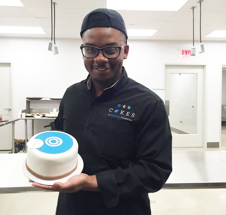 James Avant poses in the kitchen with a round cake he created.