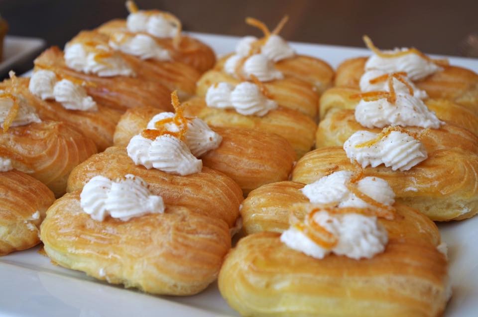 Rows of golden puff pastries topped with cream and candied orange peel, from OCD Cakes.