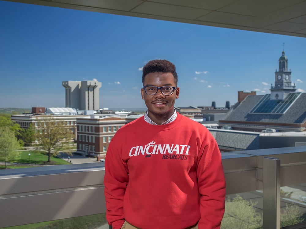 James Avant IV poses for a photo on UC's campus in a red Bearcats sweatshirt