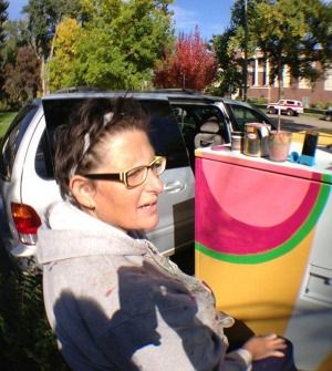 Amelia Caruso paints a transformer box in Fort Collins, Colo.