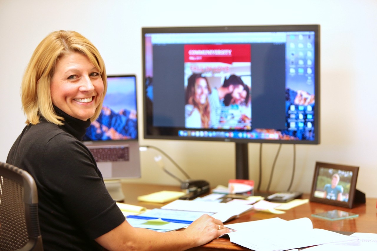 Director of UC Communiversity, Janet Staderman, sits at her desk in front of a computer that displays the Communiversity catalogue on screen.
