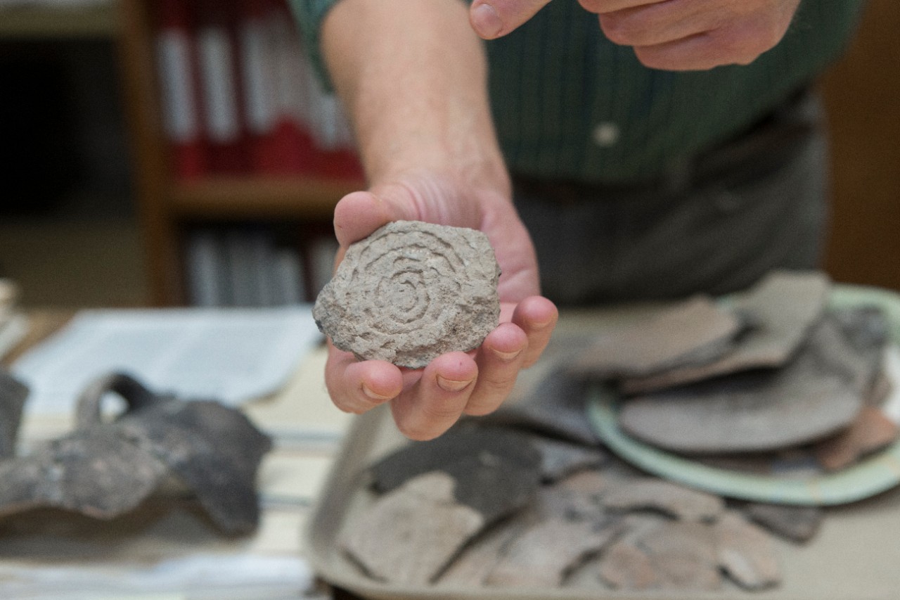 UC professor Alan Sullivan holds a pottery sherd recovered from an archaeological site in Arizona.