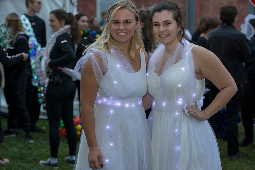 DAAP students display illuminated Body Mantle projects made from inexpensive materials and light-up components. Here, two women post in white dresses that light up.