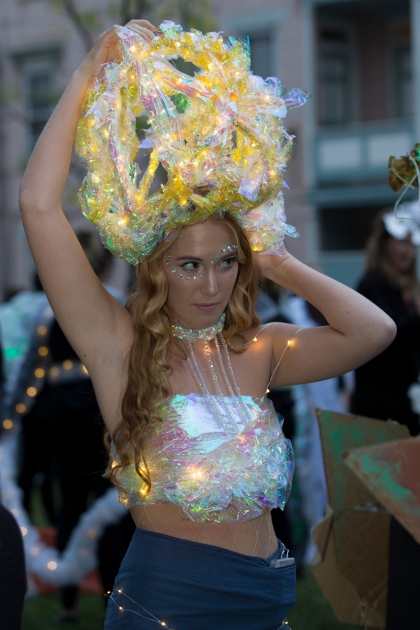 A woman ears a light up headpiece and tube top in the BLINK parade.