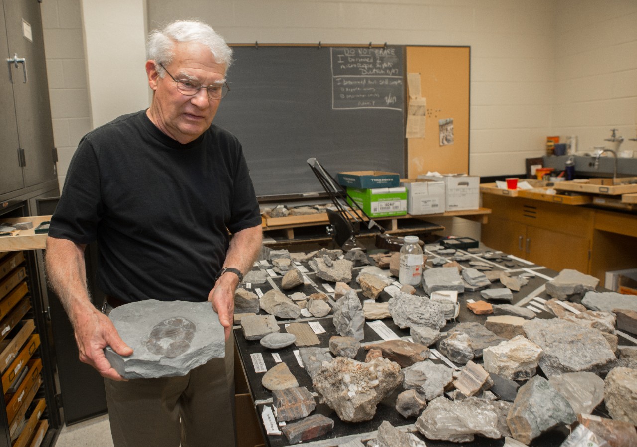 UC geology professor emeritus David Meyer holds a trilobite fossil in a UC geology lab full of specimens, some donated by the Cincinnati Dry Dredgers.