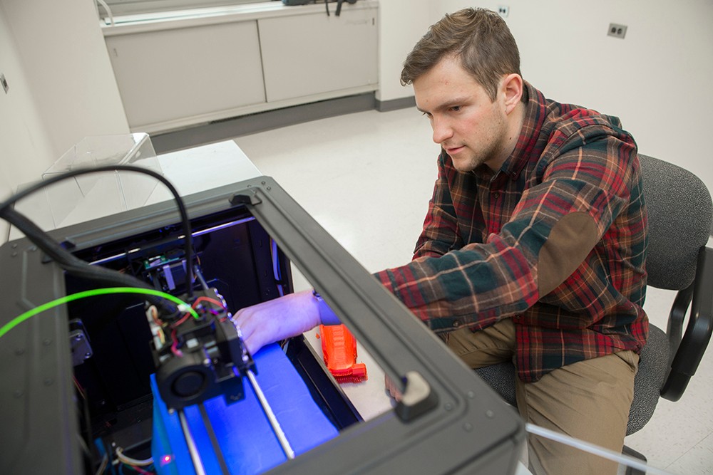 Jacob Knorr reaches into EnableUC's 3-D printer.