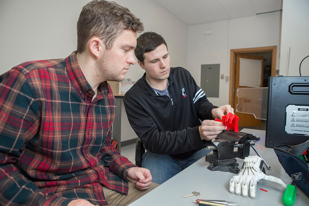 Jacob Knorr and Nick Bailey work on a 3-D printed prosthetic hand.