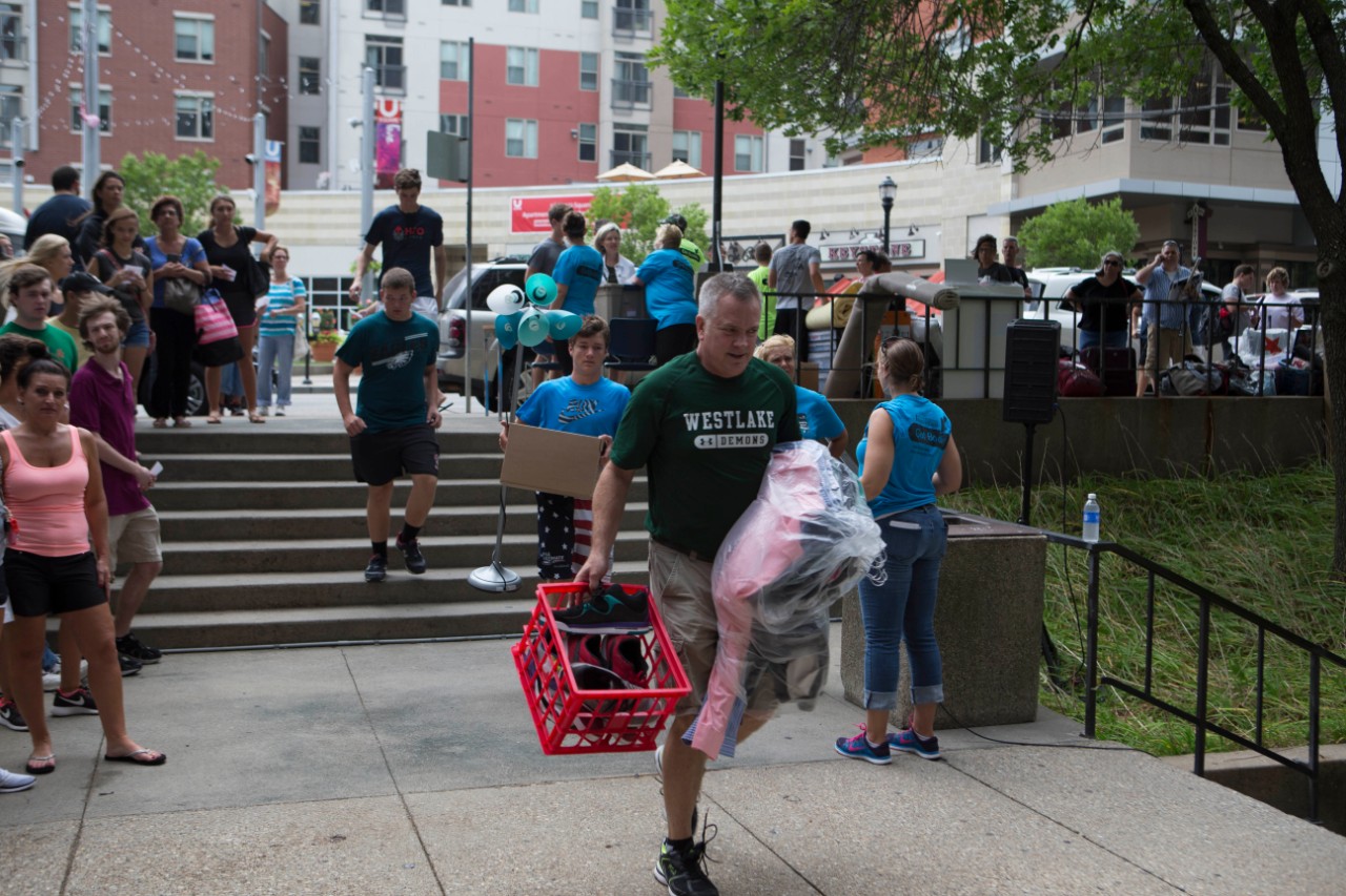 A man carries a plastic tub as students move into campus dorms.