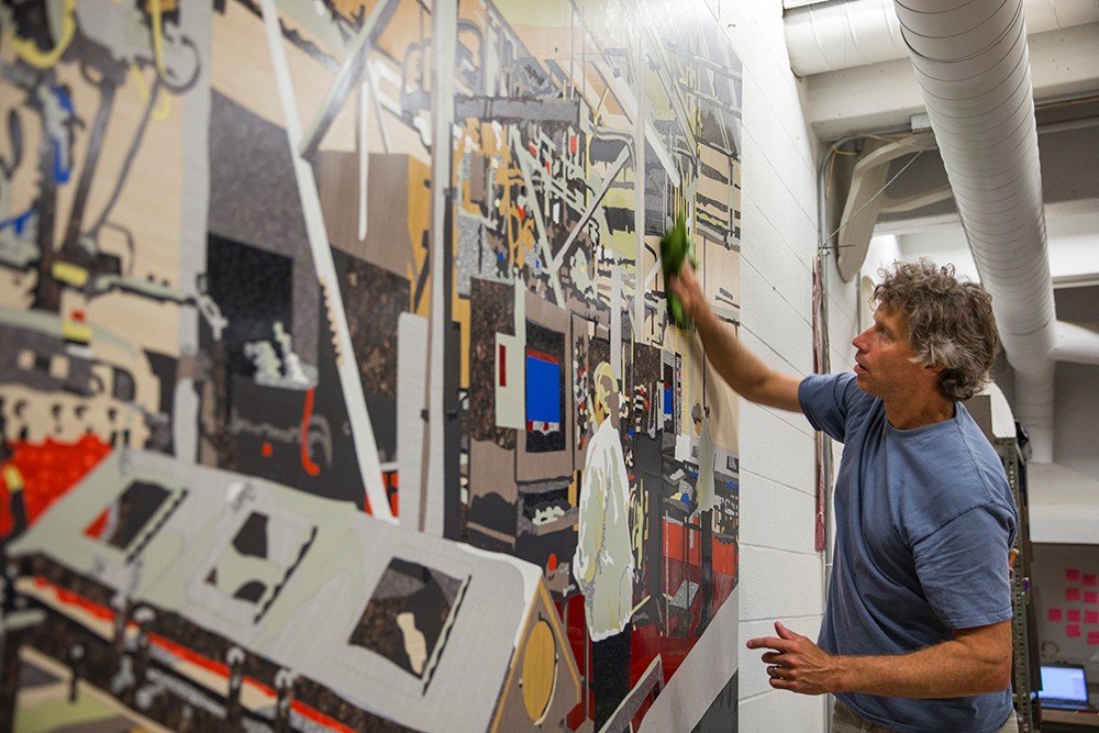 Matt Lynch cleans excess glue off a completed mosaic of the Airheads candy factory.