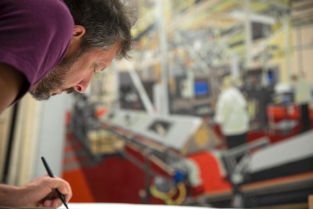 Curtis Goldstein works on a line drawing with a completed mural in the background.