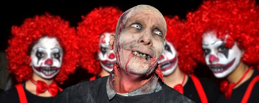 Four redheaded clowns look at a bald, gruesome bloody-mouthed evil clown in the forefront