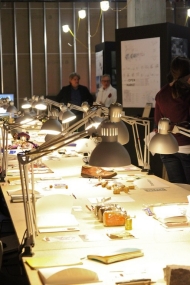 Long table with flexi-neck lamps show sketches displayed on table..