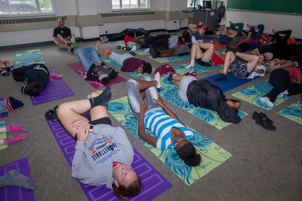 CPS students stretch on floor mats during yoga classes in UC's Blegen Library. photo/Joseph Fuqua II/ UC Creative Services
