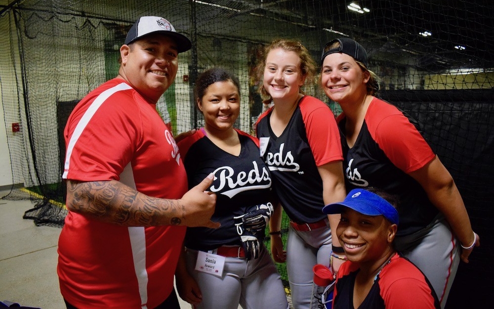 Crystl Bustos, two-time US Olympic Gold medalist stands with four CPS student softball players inside the Reds Youth Academy.