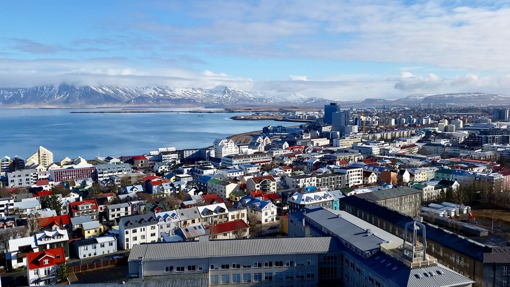 Aerial view of colorful rooftops against a blue ocean and mountains in Reykjavik, the capital city of Iceland.photo/Jacob Orkwis