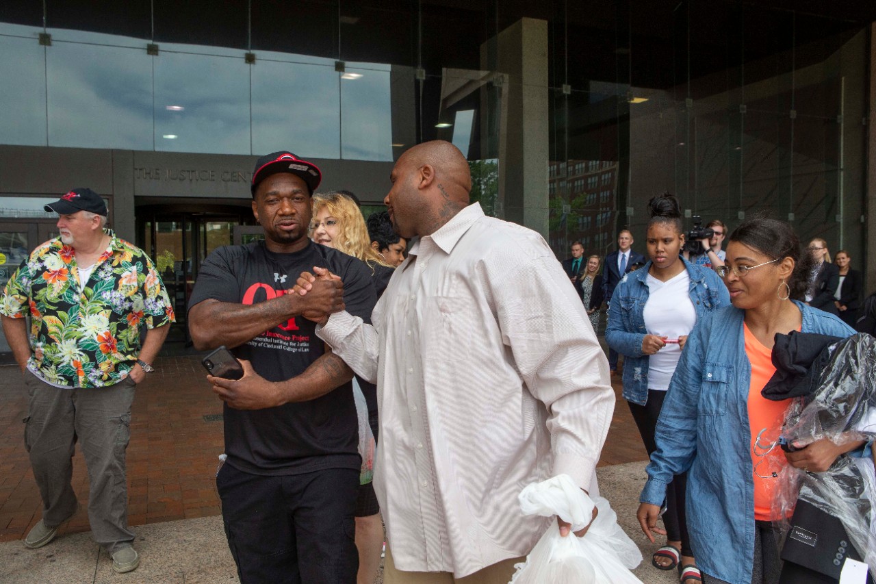 Ohio Innocence Project exonerees Dean Gillispie, far left, and Ru-El Sailor congratulate Christopher Miller on Thursday on the steps of the Cuyahoga County Justice Center. Gillispie and Sailor were released from prison with help from students and faculty at UC's College of Law and its Ohio Innocence Project.