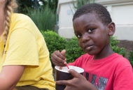 Cute African-American kid looking right at the camera while eating ice cream outside