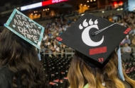 Two graduates' decorated mortarboards at the University of Cincinnati summer commencement