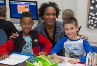 UC alumna and Olympian Mary Wineberg, an attractive African-American woman with a riot of curls, sits with students from her elementary class where she teaches.