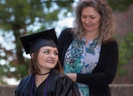 A student in a wheelchair wearing a graduation cap and gown, Tori Thomas, with her mother, Melissa Caldwell, standing behind.