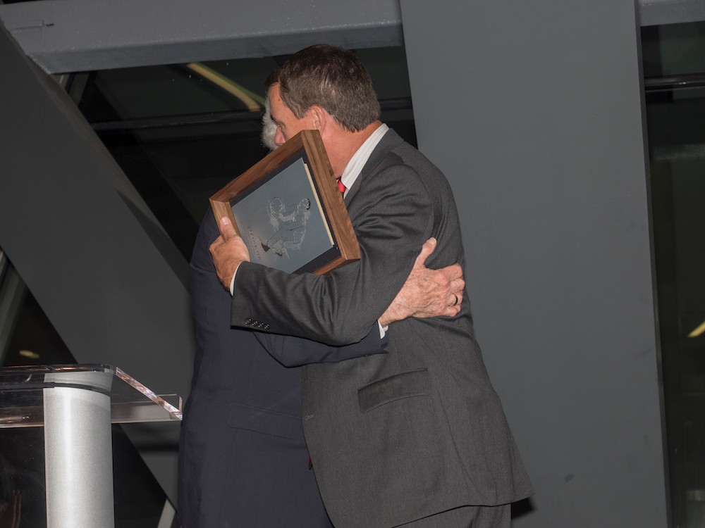 Jack Laub and Mike Bohn, UC athletics director, embrace after he leaves the podium.