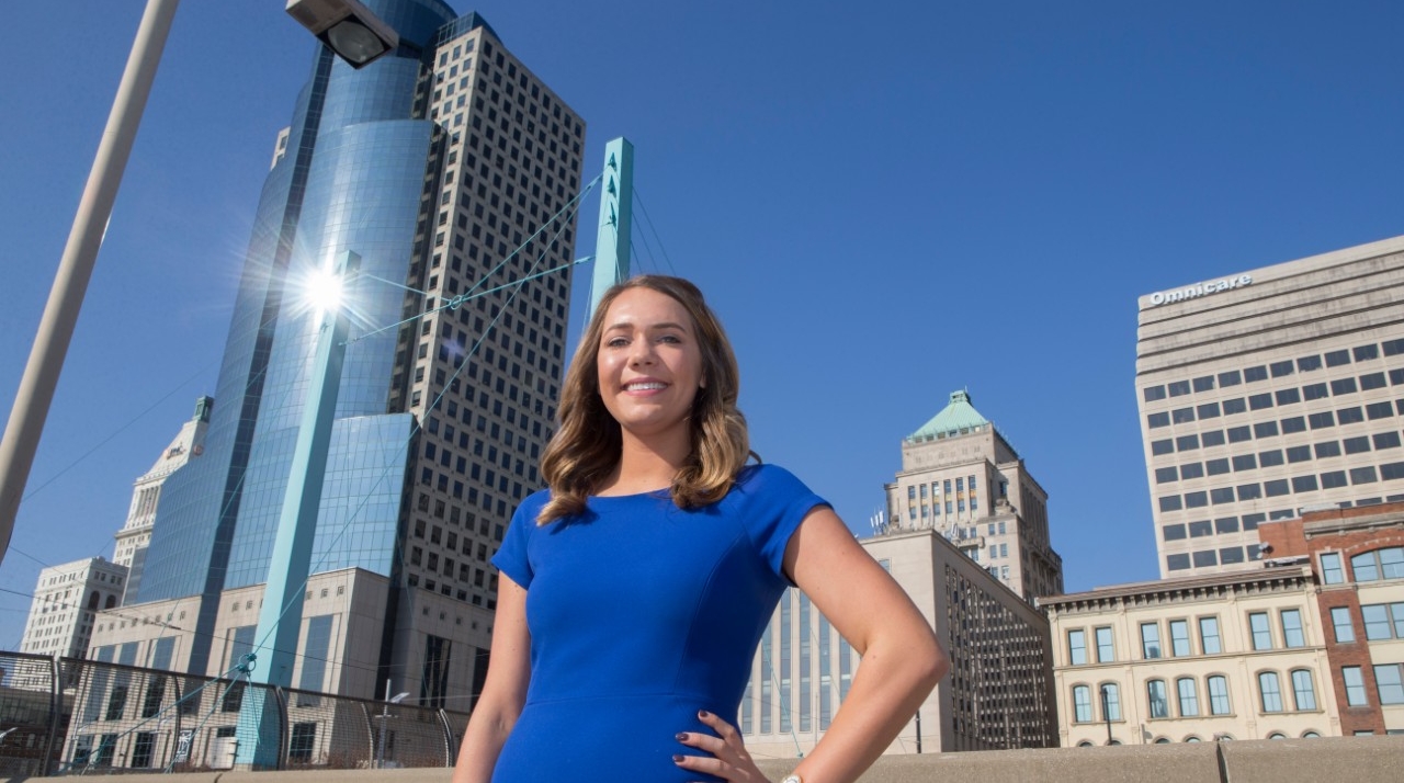 UC alum Emily Bleuher stands outside on a sunny day in downtown Cincinnati.