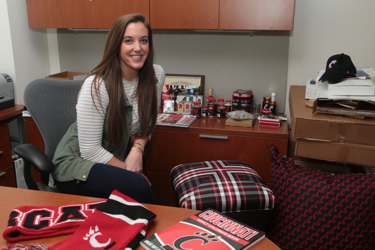 Meredith Kussmaul sits in her office showing several UC licensed products including UC's tarten plaid fabric.