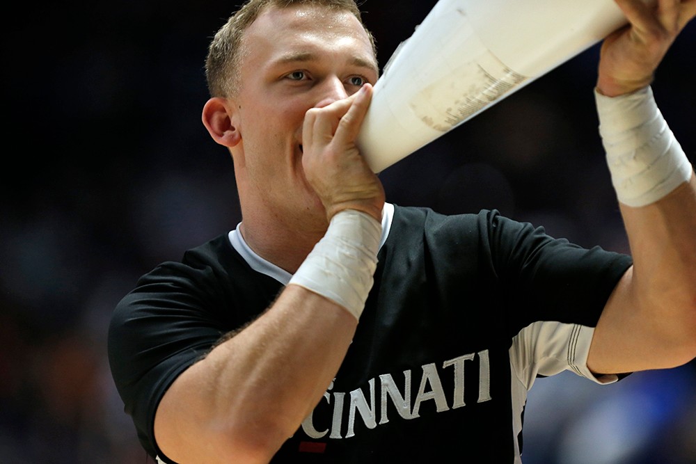 A male cheerleader shouts into a megaphone. 
